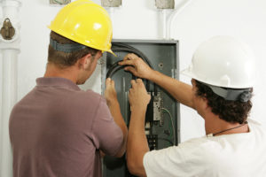 Electricians working together to install a breaker panel.