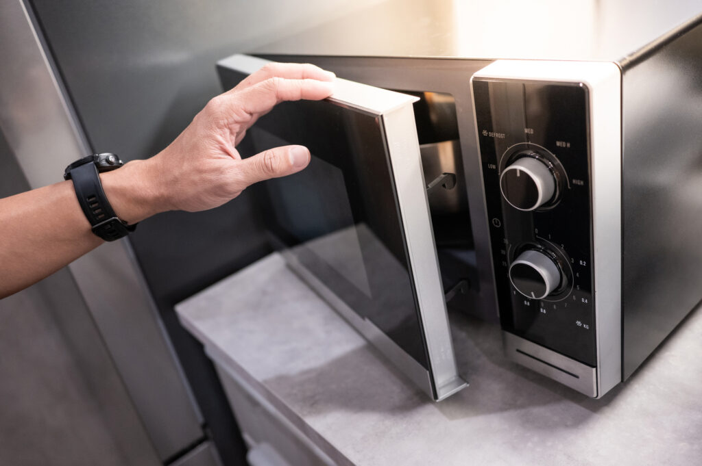 Male hand opening microwave door on the counter