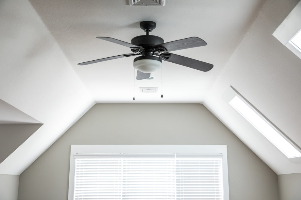 Open and airy attic room with a ceiling fan displayed